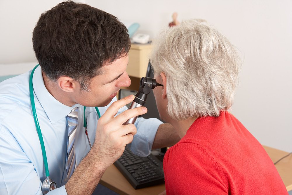 Hearing doctor examining senior woman's ear